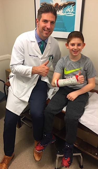 Dr. Horst and patient with Patriots themed cast sitting in exam room